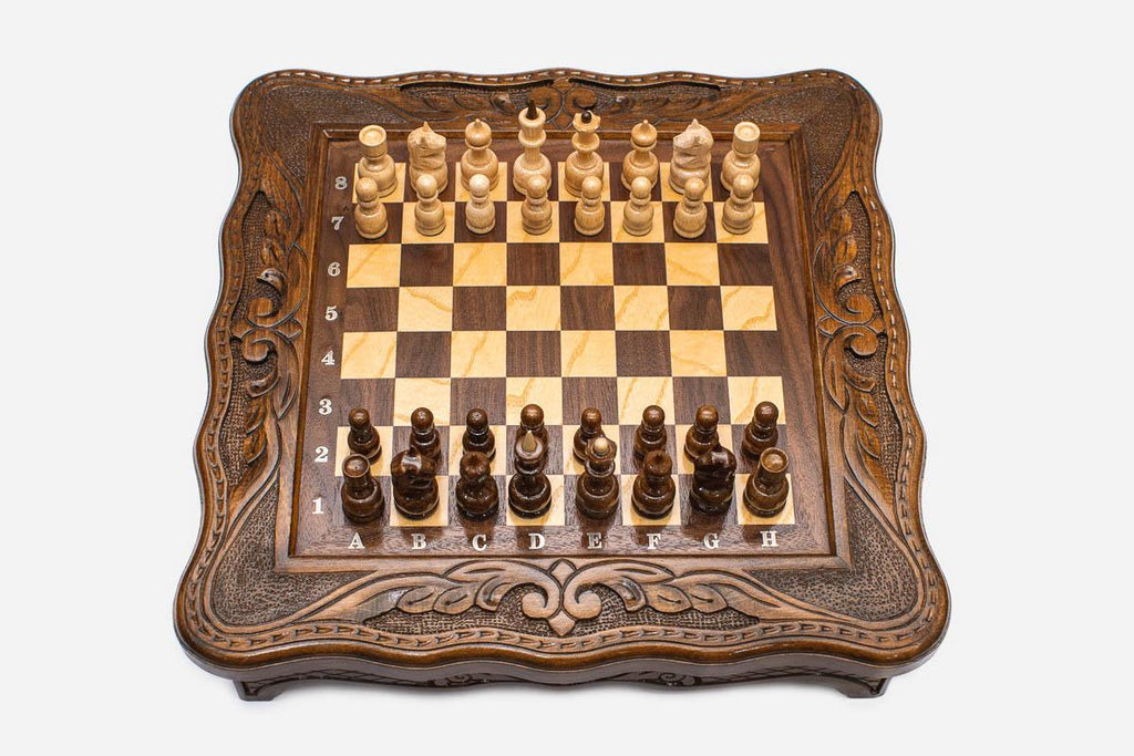 Compact carved chess set viewed from above with light and dark pieces arranged for play