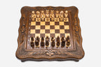 Compact carved chess set viewed from above with light and dark pieces arranged for play