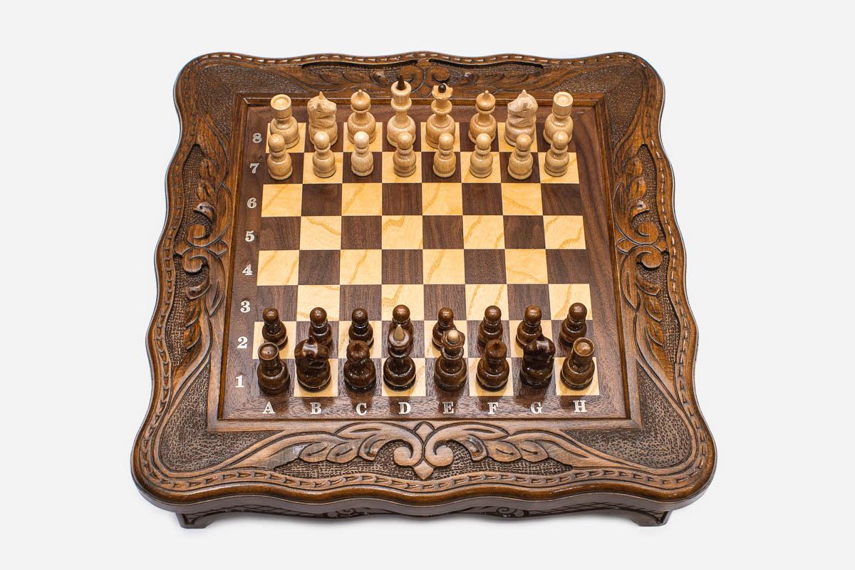 Compact carved chess set viewed from above with light and dark pieces arranged for play