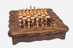 Angled view of the compact chess set with scalloped carved frame and pieces set up on the board
