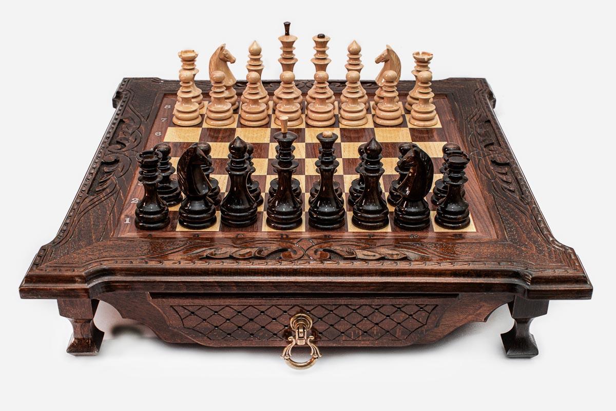Dark walnut wooden chess set with scroll-carved corners and wooden pieces set up on the inlaid board