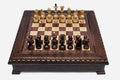 Wooden chess set in dark walnut finish with a carved lattice and beaded border and wooden pieces set up for play