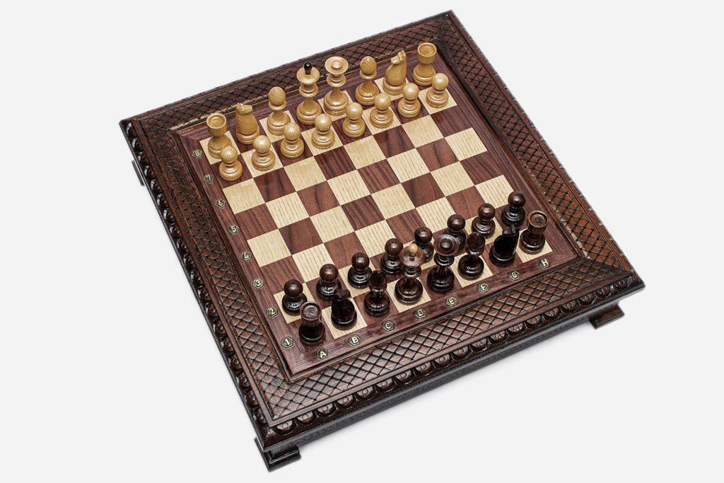 Angled top view of the dark walnut chess board with carved border and pieces arranged for play