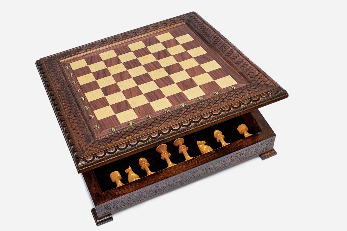 Wooden chess set with its front storage drawer pulled out, revealing the light chess pieces