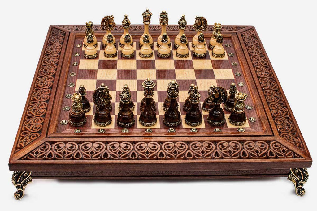 Luxury wood and brass chess set with figural gold-mounted pieces and an openwork filigree carved border, shown from the front