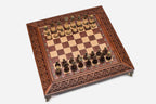 Top angle of the wood and brass chess set with intricately carved lace border and brass-collared pieces set up for play