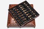 Satin-lined tray of the brass-mounted wooden chess pieces resting on the carved board