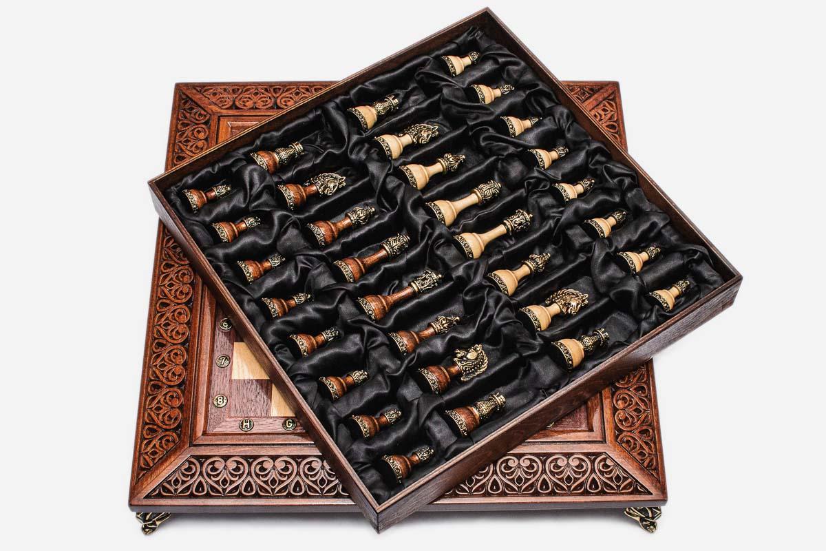 Satin-lined tray of the brass-mounted wooden chess pieces resting on the carved board