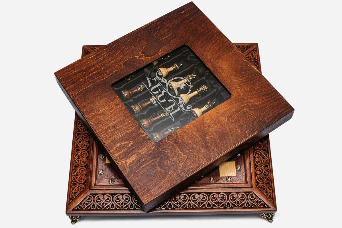 Wooden presentation box with viewing window covering the satin-wrapped chess pieces