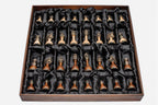 Full set of brass-mounted wooden chess pieces arranged in the black satin presentation tray