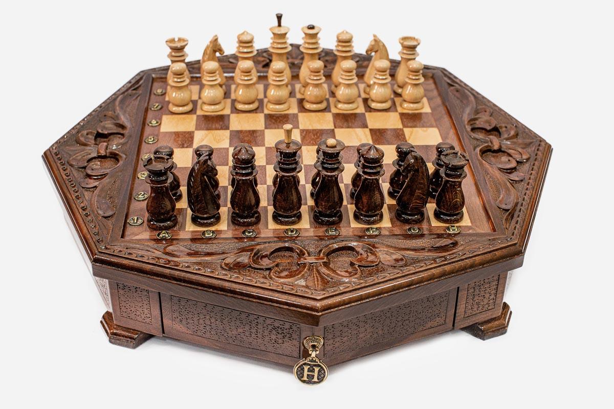 Octagonal wooden chess set with carved fleur-de-lis border and wooden pieces set up on the inlaid board