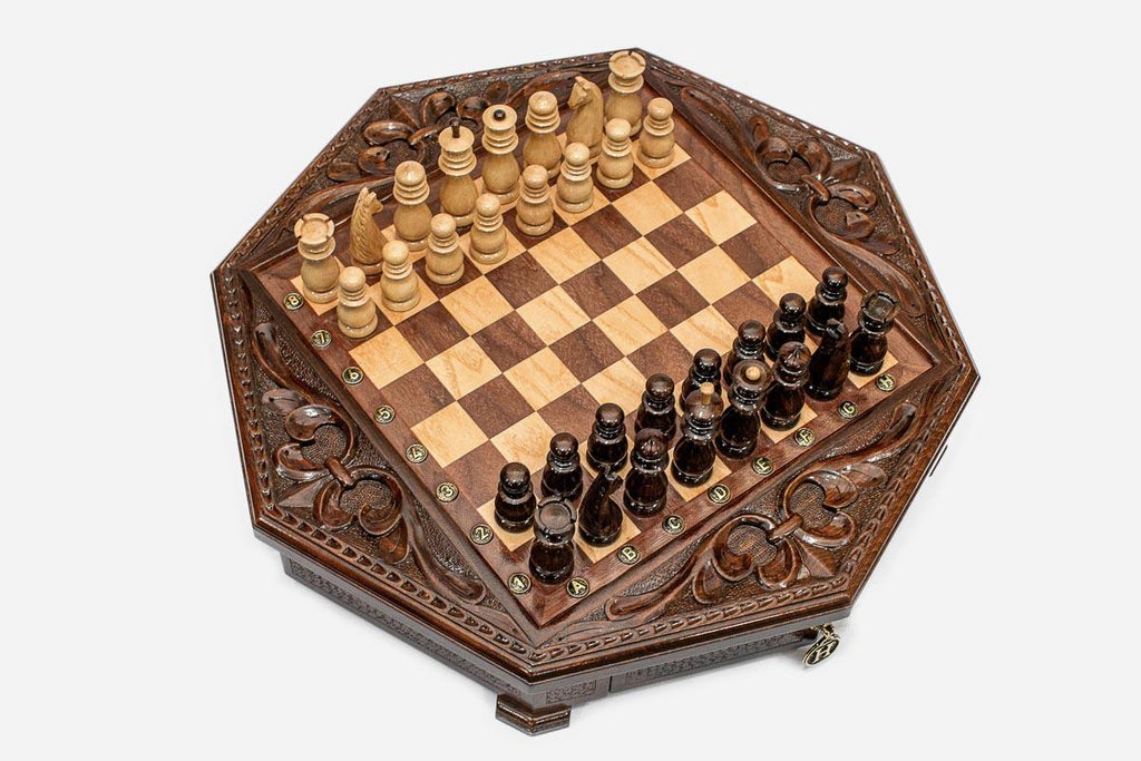 Top-down angle of the octagonal chess board with brass coordinate markers and carved fleur-de-lis corners