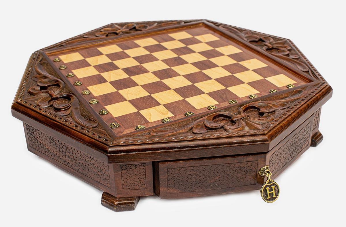 Angled view of the empty octagonal chess board with carved fleur-de-lis border and brass drawer pull