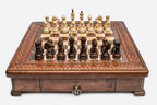 Square wooden chess set with carved diamond-lattice border and wooden pieces set up on the walnut and maple board