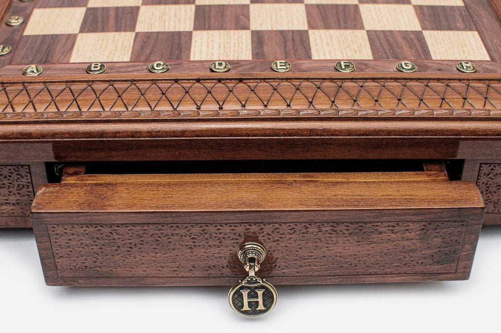 Close-up of the square chess set's carved lattice border and open storage drawer with brass pull