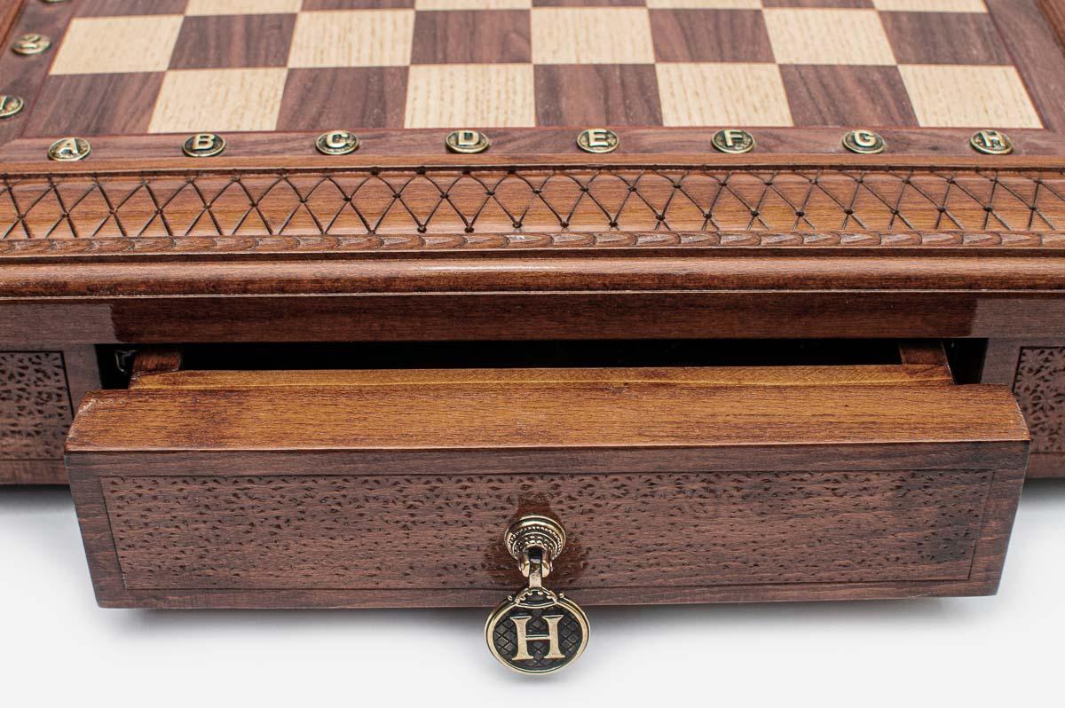 Close-up of the square chess set's carved lattice border and open storage drawer with brass pull