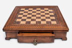 Empty square wooden chess board showing the carved border and inlaid checkered surface