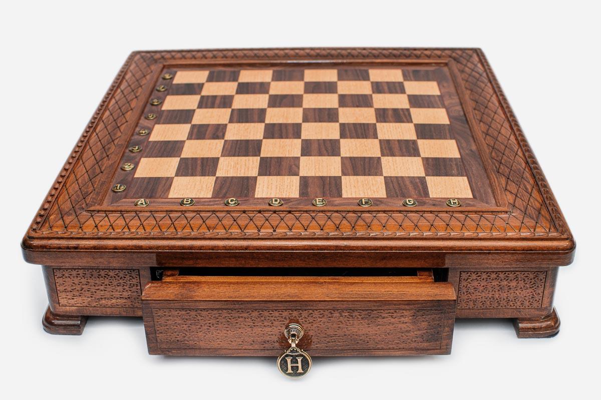 Empty square wooden chess board showing the carved border and inlaid checkered surface