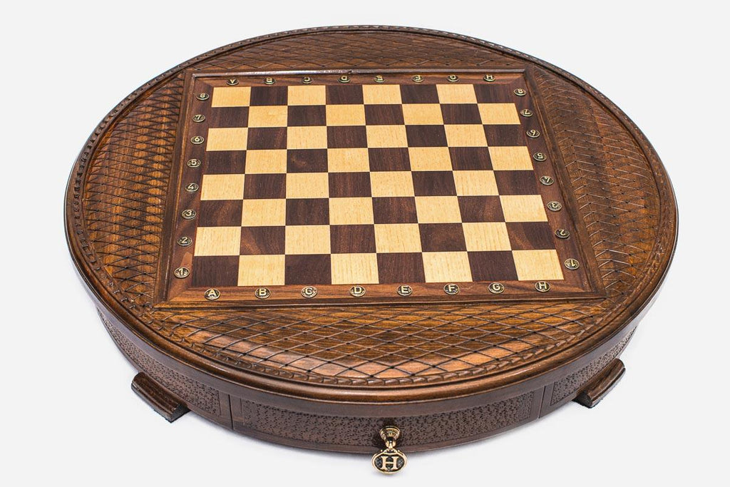 Angled view of the round carved chess set showing the diamond-lattice border and inlaid checkered board