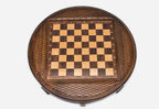 Top-down view of the round chess board with brass coordinate markers and carved basketweave frame