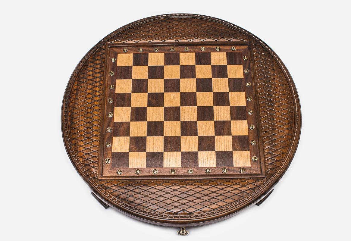 Top-down view of the round chess board with brass coordinate markers and carved basketweave frame