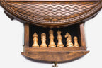 Close-up of the round chess set's open storage drawer holding the light wooden pieces