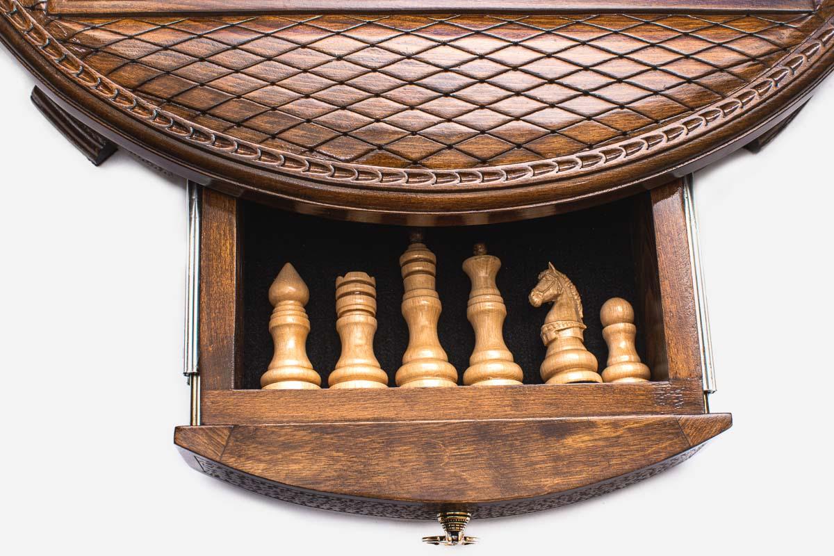 Close-up of the round chess set's open storage drawer holding the light wooden pieces