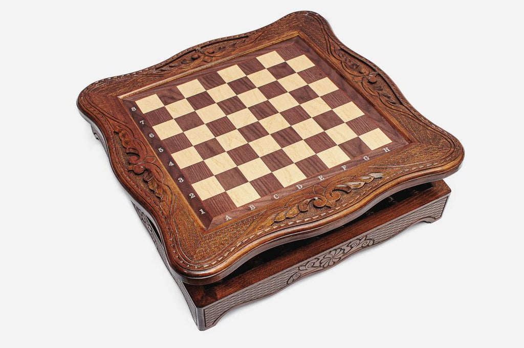 Angled view of the carved wooden chess set with its storage drawer beneath the board