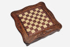 Top-down view of the empty walnut and maple inlaid chess board with carved border