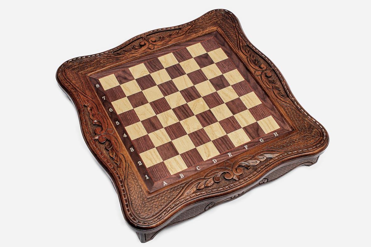 Top-down view of the empty walnut and maple inlaid chess board with carved border