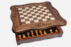 Storage drawer pulled out from the base of the chess set revealing the light wooden pieces inside