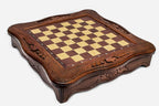 Empty carved wooden chess board showing the scalloped frame and checkered playing surface