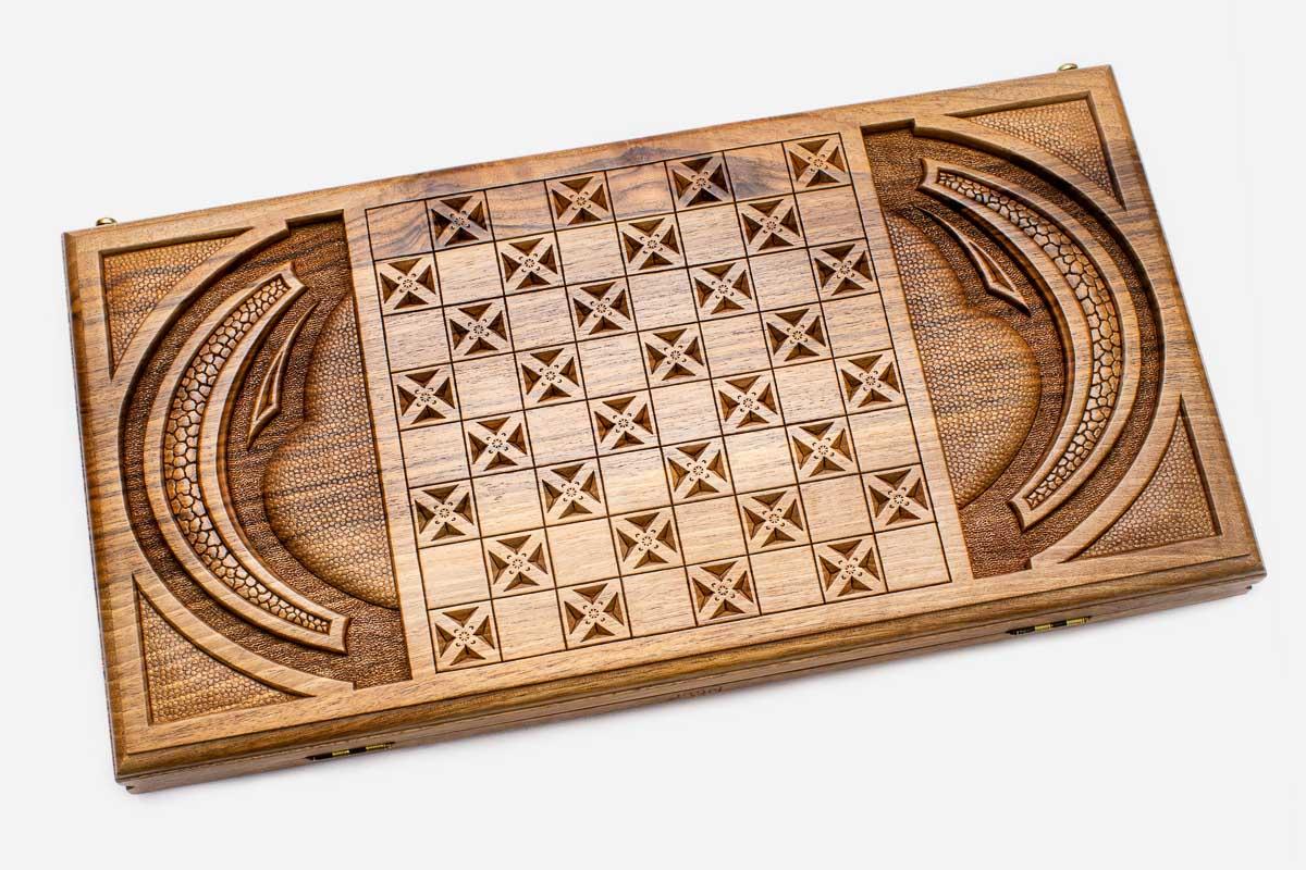 Angled view of the mask master carved walnut backgammon board