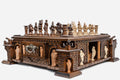 Side view of the castle chess set showing brick-carved fortress base, corner turrets with bronze cannons and figural pieces set up on the board