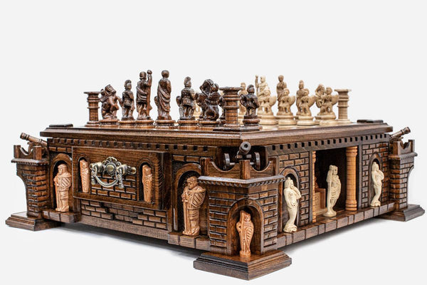 Side view of the castle chess set showing brick-carved fortress base, corner turrets with bronze cannons and figural pieces set up on the board