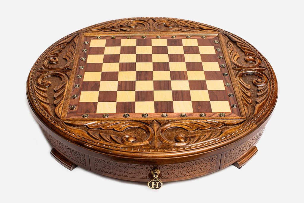 Empty round wooden chess board showing hand-carved acanthus scrollwork frame and inlaid checkered surface
