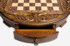 Close-up of the round chess set's open storage drawer with ornate brass pull handle and carved frame