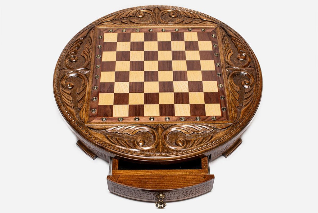 Top-down view of the round wooden chess board with brass coordinate markers and open storage drawer
