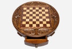 Top-down view of the round wooden chess board with brass coordinate markers and open storage drawer