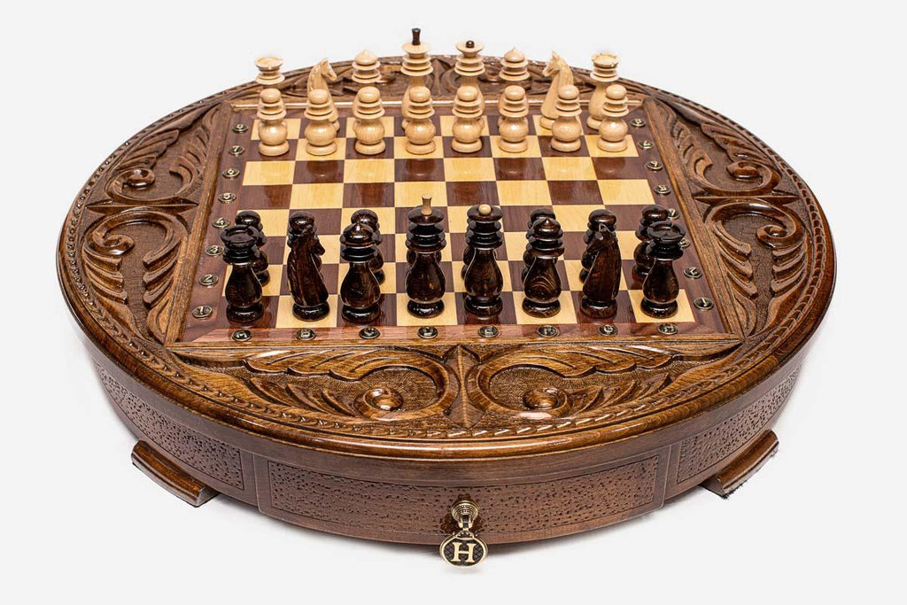 Angled view of the round carved chess set with dark and light wooden pieces arranged on the board