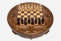 Round handmade wooden chess set with walnut and maple inlaid board and carved pieces set up for play