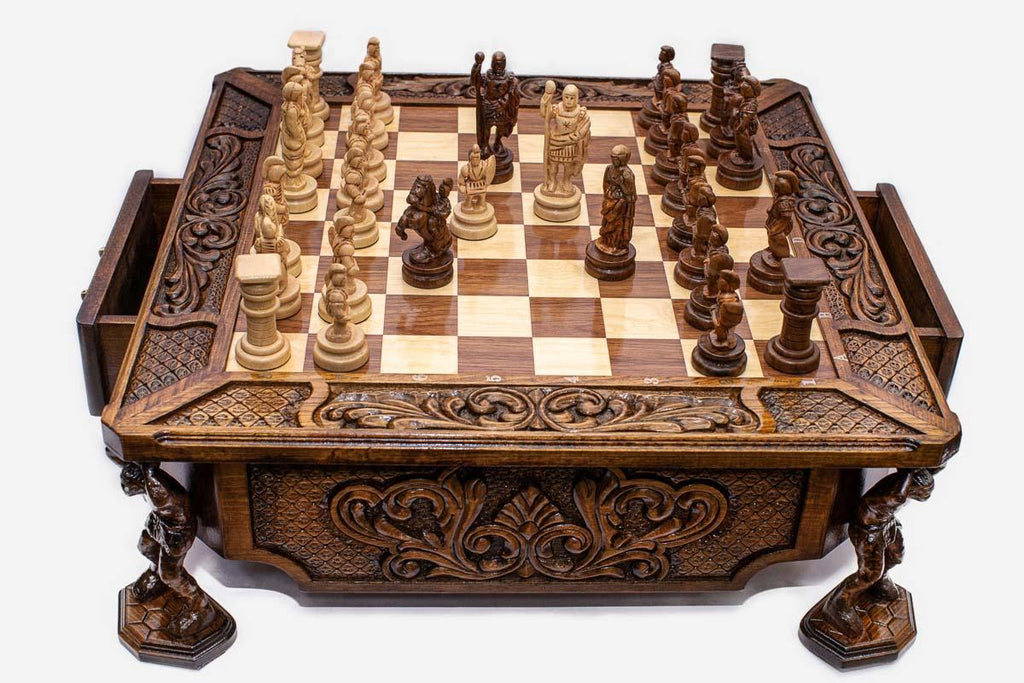 Atlant carved chess set with figural wood pieces set up mid-game, angled view