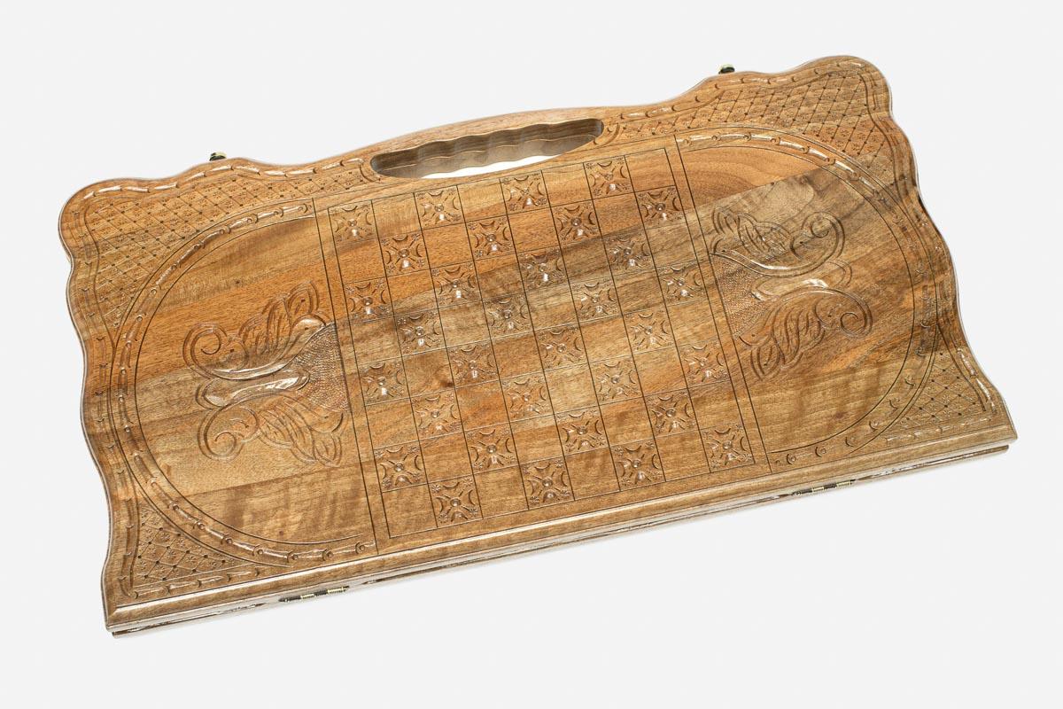 Angled view of the three scenes carved walnut backgammon board