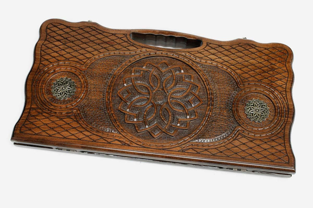 Carved beechwood backgammon board with a central carved ornament and bronze discs, propped open