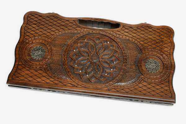 Carved beechwood backgammon board with a central carved ornament and bronze discs, propped open