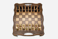 Classic walnut travel chess set with a carved lattice border and built-in carry handle, pieces in starting position