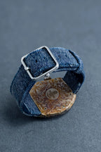 Denim bracelet with a metal clasp on a gray background