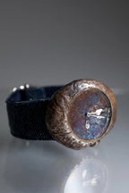 Rust-colored metal button on a black fabric background