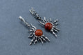 Silver earrings with red stones on a gray background