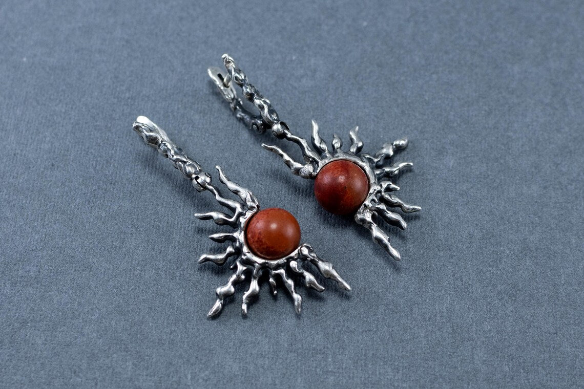 Silver earrings with red stones on a gray background